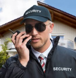 Close-up Of A Young Male Security Guard Using Walkie-talkie In Front Of A House